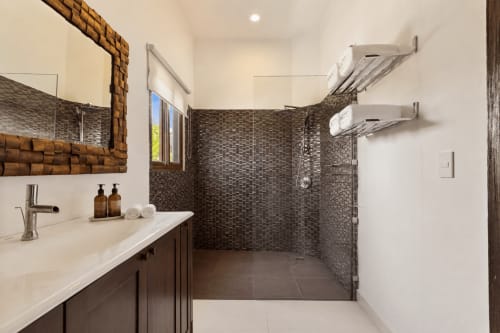 Modern bathroom with dark tile walk-in shower, white vanity, and heated towel racks at Casa Javi Ocean Front cottage in Isla