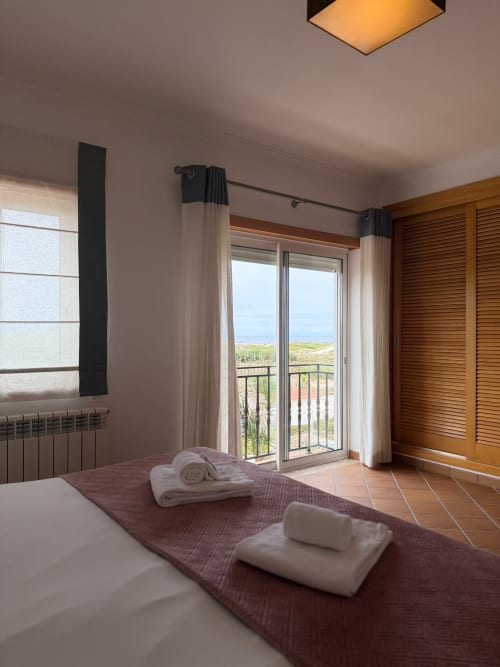 Quarto à beira-mar no Be SilverCoast em Serra D'El Rei com vista para o mar, toalhas enroladas e acesso à varanda