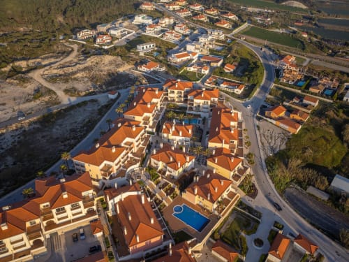 Vista aérea do resort Be SilverCoast em Serra D'El Rei com casarões de telhados laranja, piscina compartilhada e vistas do rio