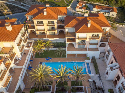 Vista aérea do hotel Be SilverCoast em Serra D'El Rei com piscina azul, palmeiras e apartamentos com telhados laranja