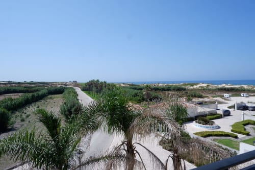 Vista de casa geminada costeira em Be SilverCoast, Serra D'El Rei, com palmeiras, lagoa e horizonte do mar
