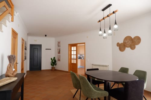 Área de jantar moderna em lindosa casa em série em Be SilverCoast, Serra D'El Rei com mesa redonda preta, cadeiras verdes e pendente