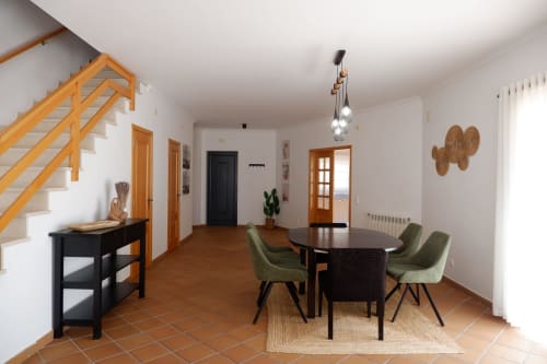 Área de jantar moderna em townhouse Be SilverCoast com escadas de madeira, mesa redonda, cadeiras verdes e decoração interior costeira portuguesa
