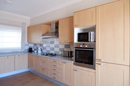 Cozinha moderna em moradia Be SilverCoast com gabinetes em madeira clara, eletrodomésticos em aço inoxidável e backsplash em azulejo em Serra