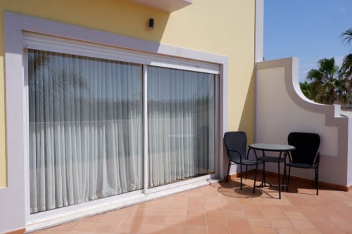 Varanda ensolarada com vista para o mar no hotel Be SilverCoast, Serra D'El Rei, com assentos ao ar livre e portas de vidro