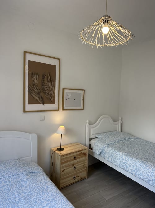 Chambre twin aux Villas Simone Porto Santo avec lits blancs, table de nuit en bois, lampe suspendue et tableau feuille de palmier