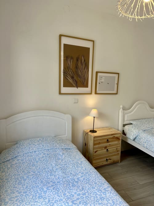 Chambre lumineuse de l'appartement Porto Santo avec lits jumeaux, table de nuit en bois et tableau botanique encadré