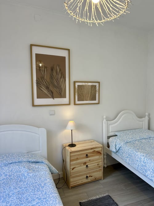 Chambre twin avec parure de lit à motifs bleus, table de nuit en bois, art botanique en cadre laiton, et luminaire au plafond au Porto