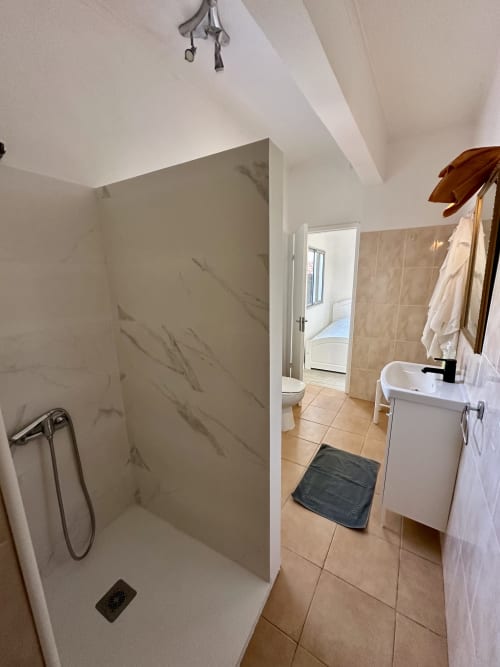 Salle de bain moderne aux Villas Simone Porto Santo avec douche à l'italienne, lavabo et carrelage en terre cuite