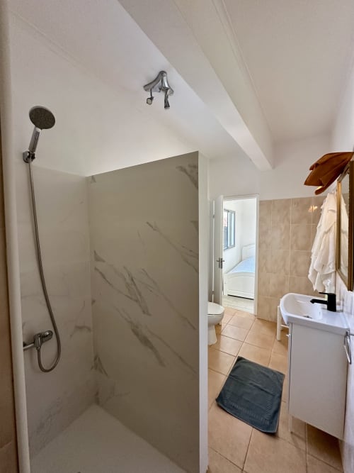 Salle de bain moderne avec douche à l'italienne, lavabo blanc et porte-serviettes chauffant aux Villas Simone Porto Santo