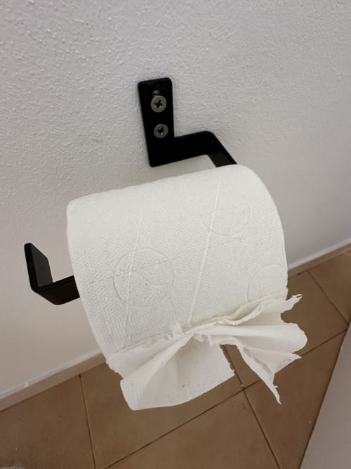 Rouleau de papier toilette blanc sur porte-rouleau noir fixé au mur dans la salle de bain de l'appartement Porto Santo