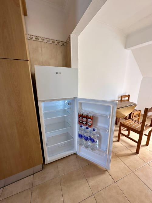 Réfrigérateur blanc Edes ouvert avec bouteilles d'eau et boissons dans la cuisine de l'appartement Porto Santo