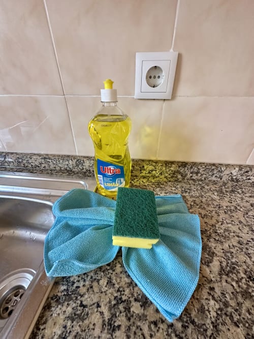 Comptoir de cuisine aux Villas Simone avec savon à vaisselle, éponge et torchon bleu près de l'évier et prise électrique