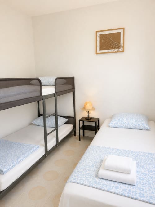 Quarto familiar nas Villas Simone Porto Santo com beliches, cama individual, almofadas azuis e quadros emoldurados