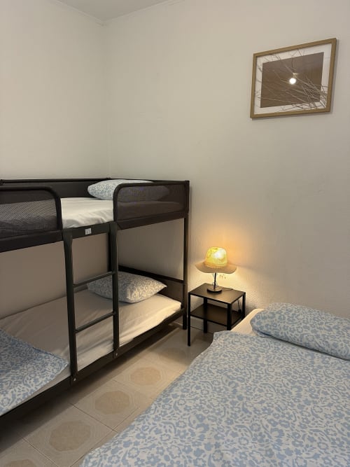 Quarto familiar com camas beliche, roupas de cama estampadas, luminária aconchegante e obras de arte moldadas nas Villas Simone Porto Santo