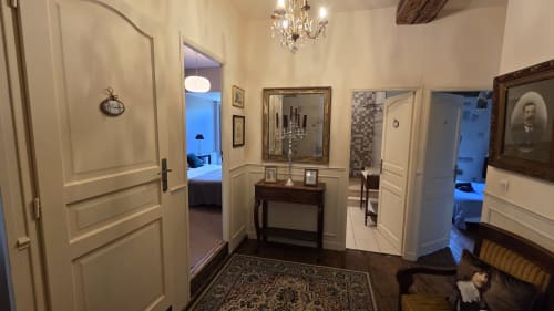 Élégant couloir du Manoir de la Bégaudière à Mont-Dol avec murs crème, lustre en cristal, console et portes