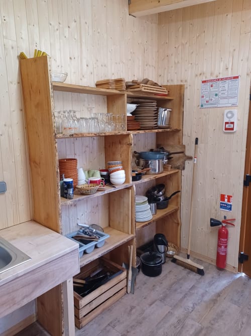 Étagères en bois rustique avec batterie de cuisine et vaisselle dans l'hébergement insolite La Yourte Un Autre Monde, Le Hohwald