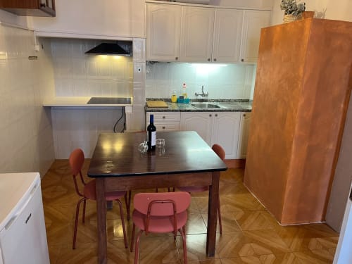 Cozinha e sala de jantar do apartamento Casa do Taxista com mesa de madeira, cadeiras vermelhas e móveis brancos em Porto Santo