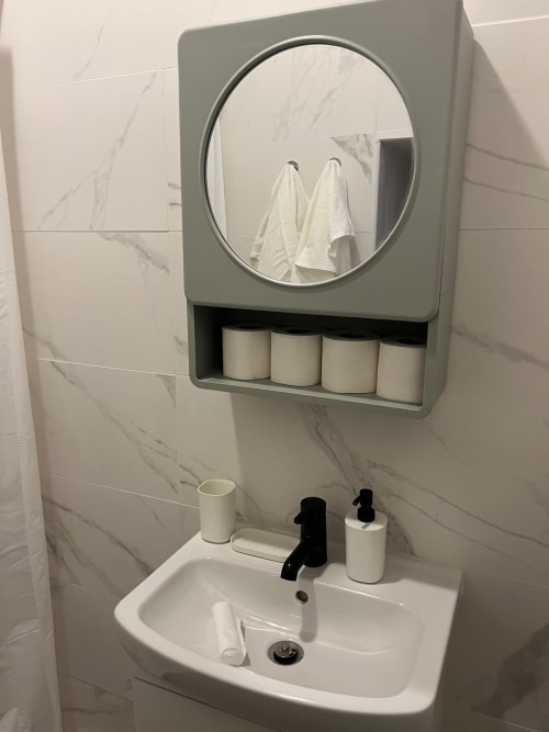 Banheiro moderno com espelho circular e armazenamento nos apartamentos Villas Simone Porto Santo