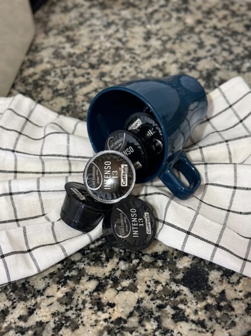 Cápsulas Nespresso e recipiente azul sobre toalha xadrez no apartamento Villas Simone Porto Santo