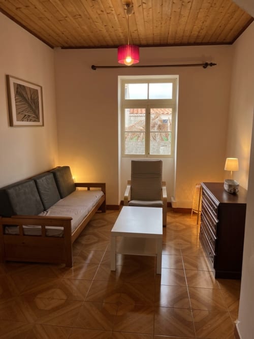 Sala aconchegante do apartamento Casa do Taxista em Porto Santo com teto de madeira, sofá, poltrona e porta de vidro para a varanda