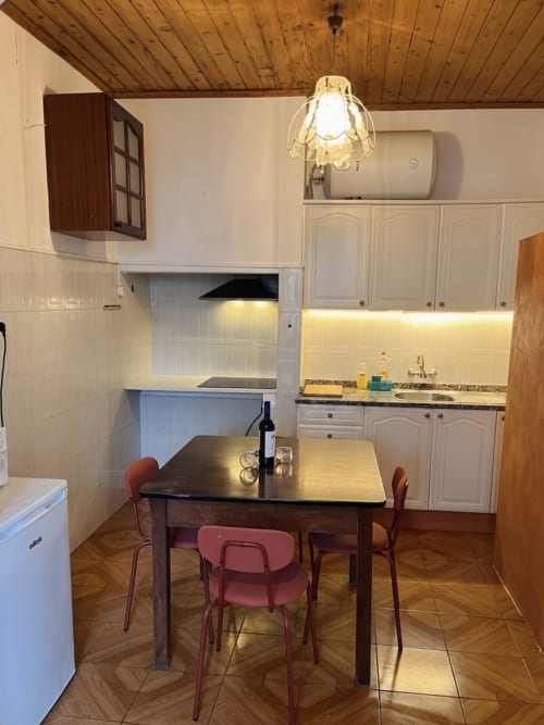 Cozinha e área de refeições do apartamento Casa do Taxista em Porto Santo com mesa de madeira, cadeiras vermelhas e kitchenette equipada
