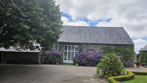 Stone manor house with purple flowers at Manoir de la Bégaudière, Mont-Dol
