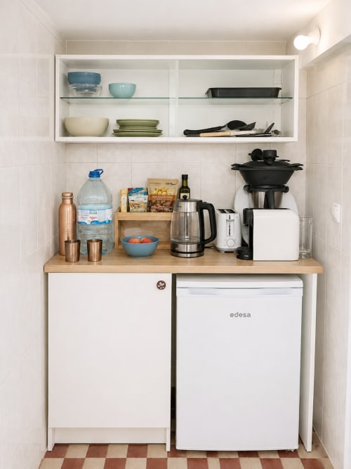 Compact kitchenette in Family Loft at Villas Simone Porto Santo with organized shelving, appliances, and blue accents