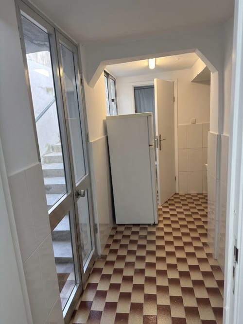 Kitchen hallway at Villas Simone Porto Santo with checkered tile floor, white refrigerator, and glass doors to patio