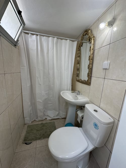 Bathroom at Villas Simone Porto Santo with toilet, pedestal sink, shower curtain, and ornate mirror