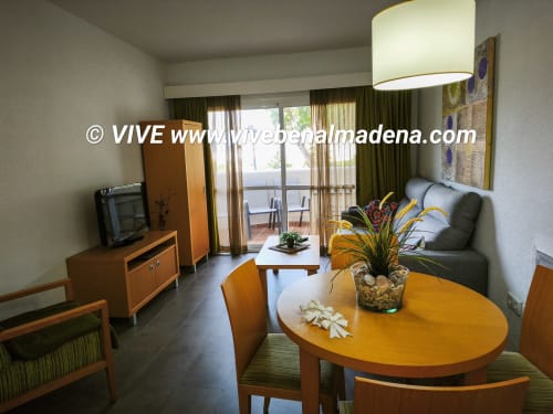 Spacious apartment living room at VIVE Benalmádena with dining area, garden view, sofa, and modern amenities