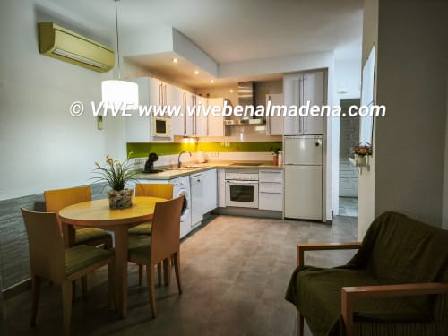 Modern kitchen and dining area with garden views at VIVE Benalmádena apartment, featuring white cabinetry and round dining
