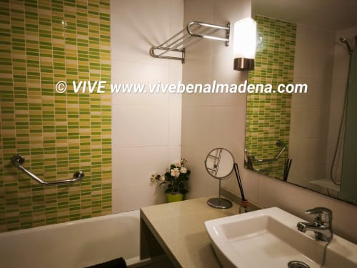 Modern bathroom at VIVE Benalmádena with green mosaic tiles, double white sinks, and contemporary fixtures