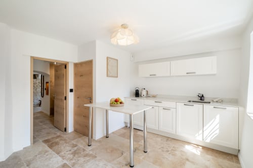Modern kitchen with white cabinetry, island, and dining area in Villa M de Mas villa in Grasse, France