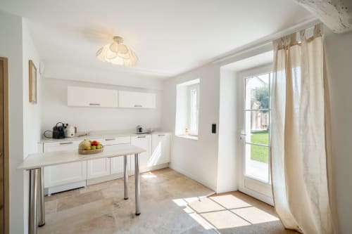 Bright modern kitchen in Villa M de Mas, Grasse, with white cabinetry, island counter, and garden view through glass doors