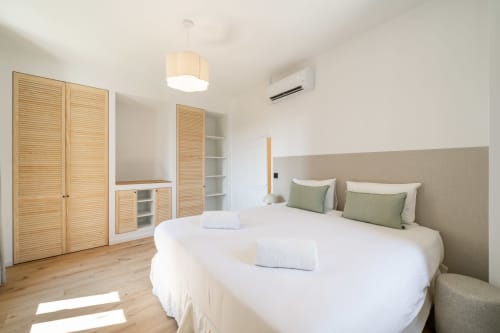 Modern bedroom with double bed, green pillows, wooden wardrobe, and built-in storage in Villa M de Mas-Piscine, Grasse