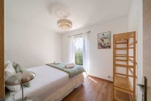 Bright bedroom in Villa M de Mas-Piscine near Cannes with wooden flooring, white bedding, and garden view