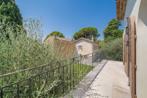 Sunny terrace with railing at Villa M de Mas near Grasse, overlooking stone houses and Mediterranean landscape