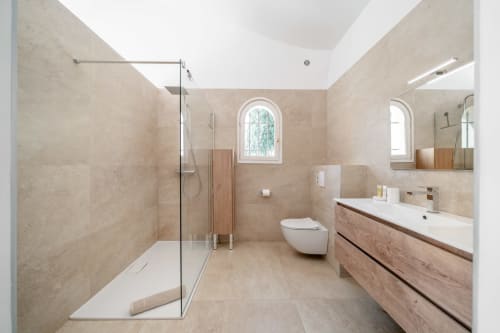 Modern bathroom in Villa M de Mas-Piscine, Grasse with walk-in shower, dual sink vanity, toilet, and arched windows