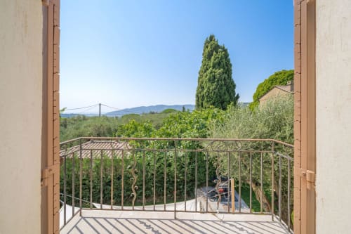 Grasse villa terrace overlooking Mediterranean landscape with cypress tree and distant bridge view