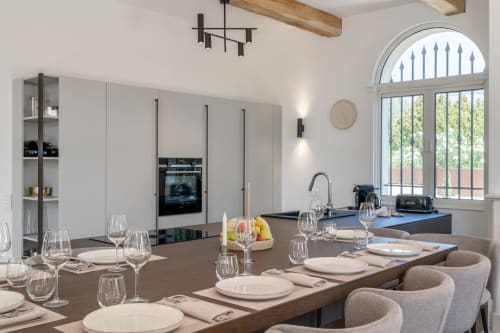 Modern dining area in Villa M de Mas-Piscine, Grasse with set table, kitchen, and arched windows