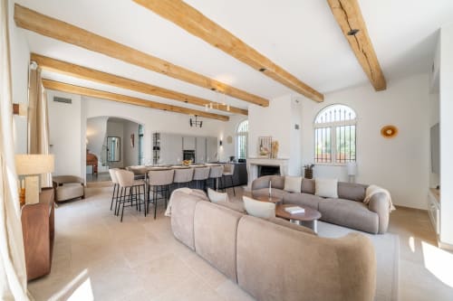 Bright open-plan living area in Villa M de Mas near Cannes with exposed wooden beams, comfortable seating, dining space,