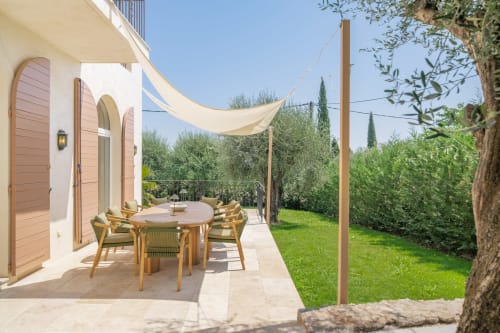 Modern villa terrace in Grasse with dining table, shade sail, and manicured gardens overlooking olive trees and landscape