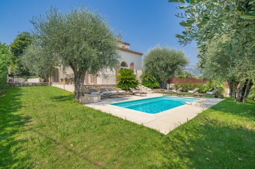 Mediterranean villa in Grasse with private pool, olive trees, and manicured gardens under clear blue sky