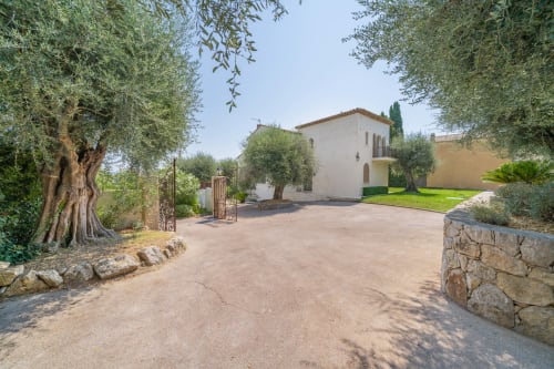 Tuscan-style villa in Grasse with olive trees, stone entry gate, and manicured grounds