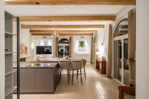 Modern villa dining and kitchen area with exposed wooden beams, dining table for 10, and contemporary furnishings in Grasse
