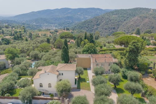 Aerial view of Villa M de Mas in Grasse with terracotta-roofed houses, olive trees, and mountain valley backdrop