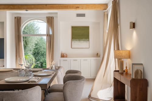 Elegant dining room at M Résidences et Hôtels with arched window, neutral tones, and modern furnishings