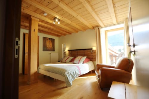 Dormitorio luminoso con vigas vistas en la cabaña Le ValOmbré de Saint-Pierre-de-Chartreuse, vistas a las montañas, detalles en cuero