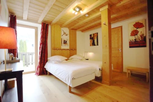 Amplio dormitorio de cabaña de madera en Le ValOmbré con cama queen, vistas a las montañas, balcón y decoración alpina rústica